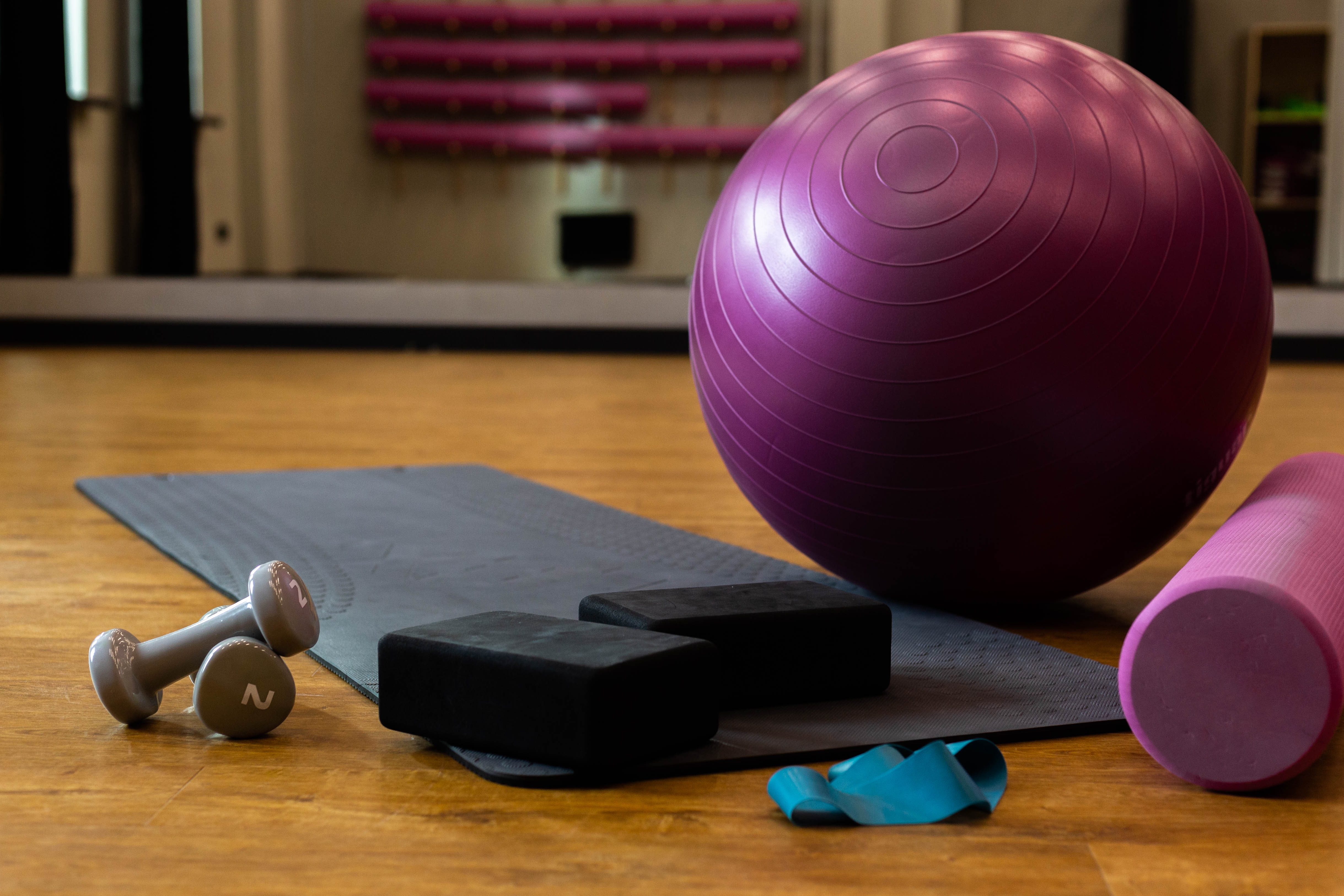 Pilates equipment including fitness ball, yoga mat, dumbbells, and foam roller